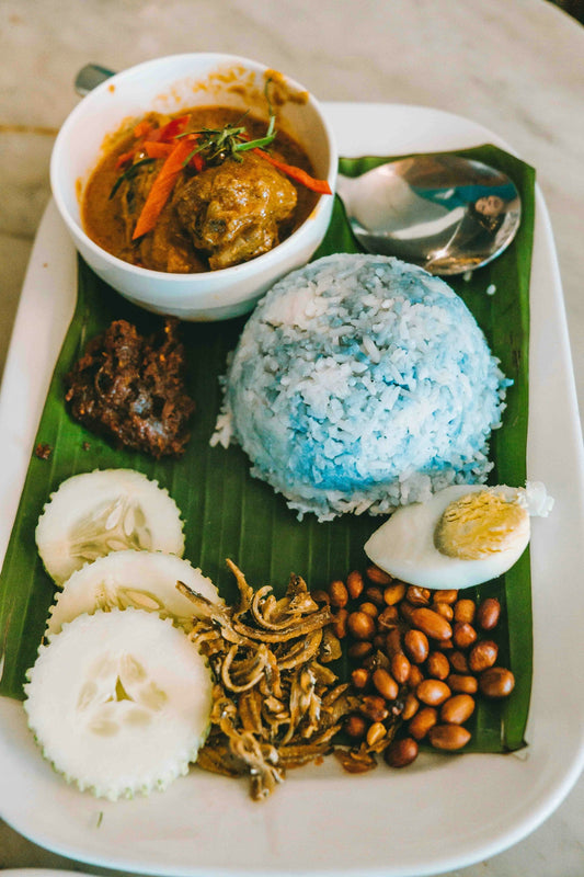 A white plate topped with rice, meat and other foods